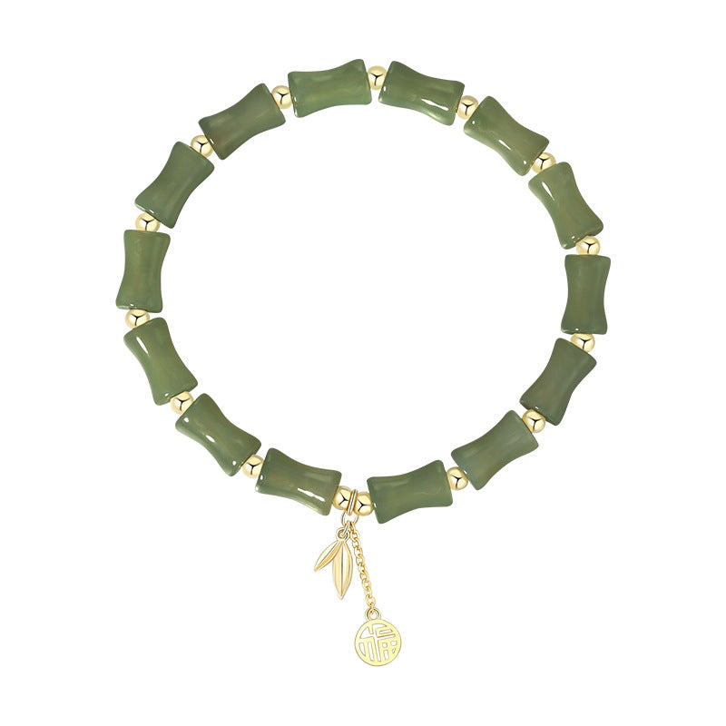 Green bracelet with gold charms on a white background