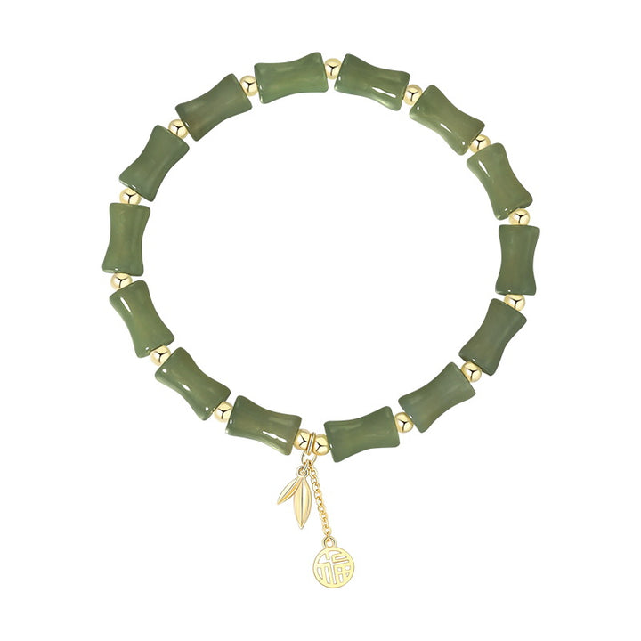 Green bracelet with gold charms on a white background