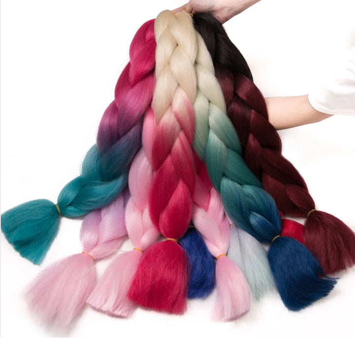 Colorful braided hair extensions held by a person on a white background