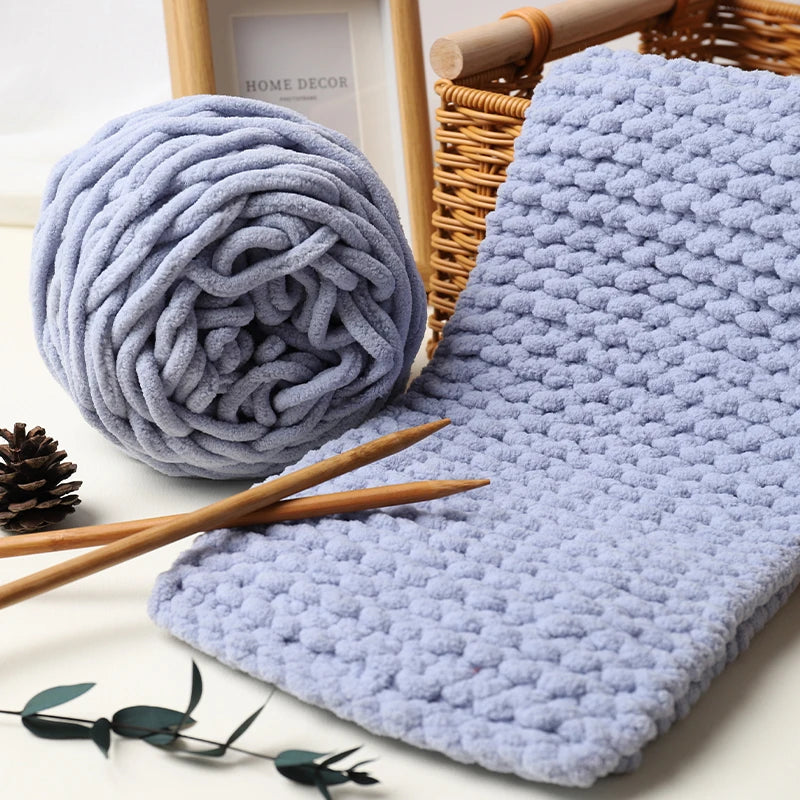 Blue textured yarn and knitting needles on a white surface with a framed picture in the background.