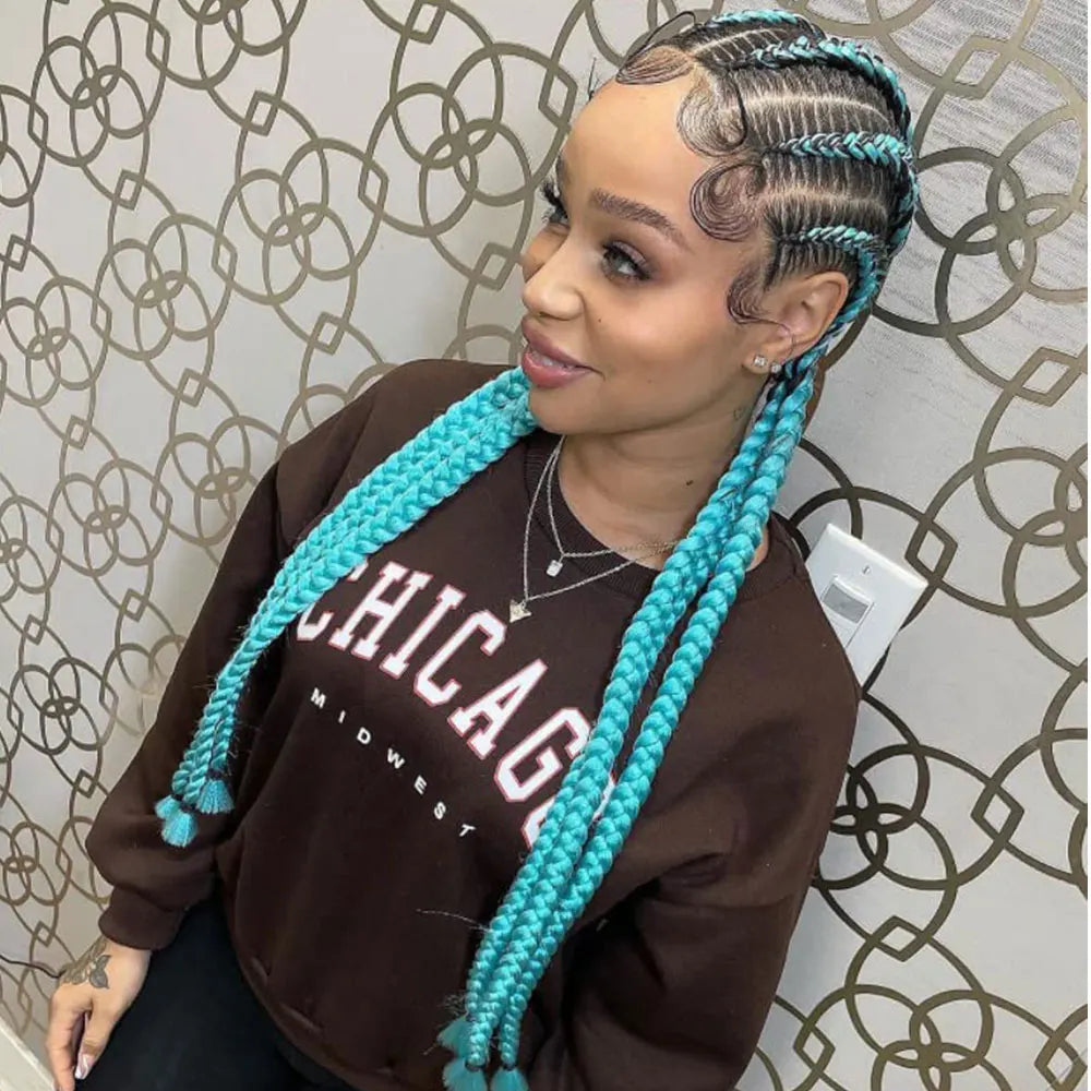 Woman with turquoise braids wearing a brown sweatshirt with 'Chicago' text against a patterned wall.