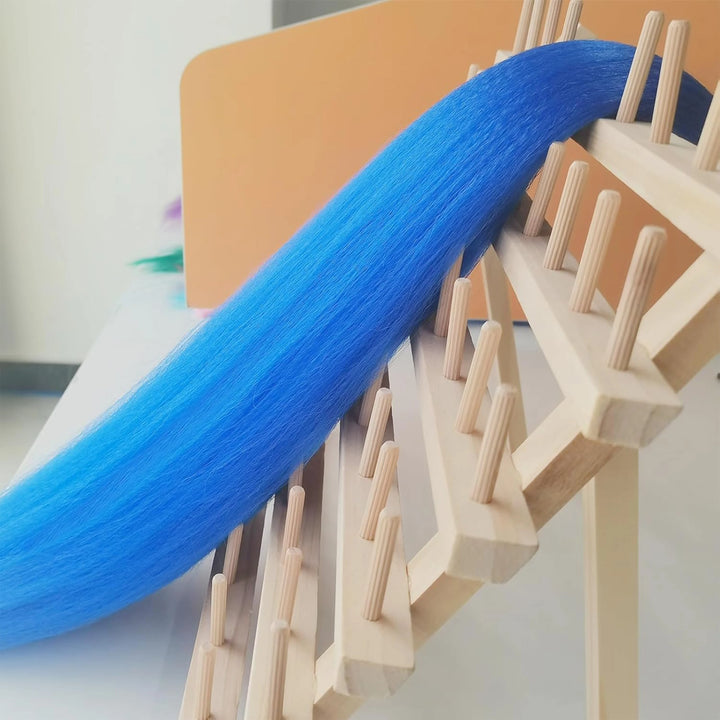 Blue thread passing through a wooden loom on a white background