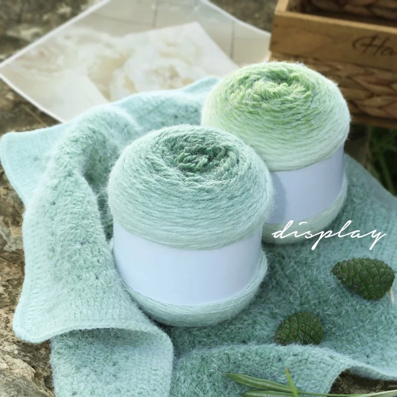 Two green skeins of yarn on white stands with a textured green fabric and decorative elements in the background.