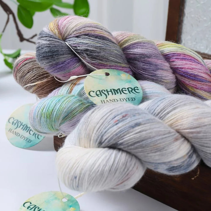 Bundles of hand-dyed cashmere yarn with visible labels on a white surface.