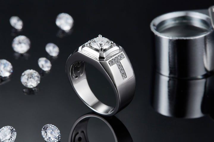Silver ring with a large diamond and smaller diamonds on a reflective black surface