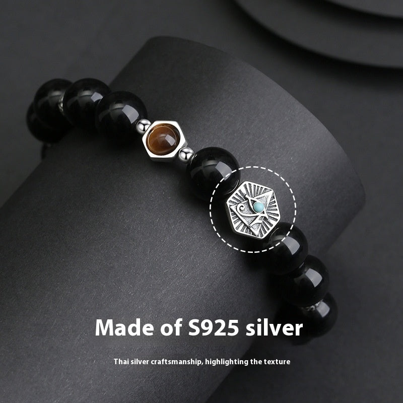 Black beaded bracelet with silver and gemstone accents on a dark surface