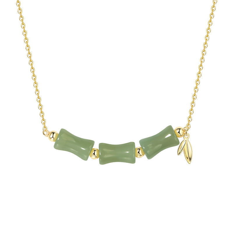 Gold necklace with green jade-like beads on a white background