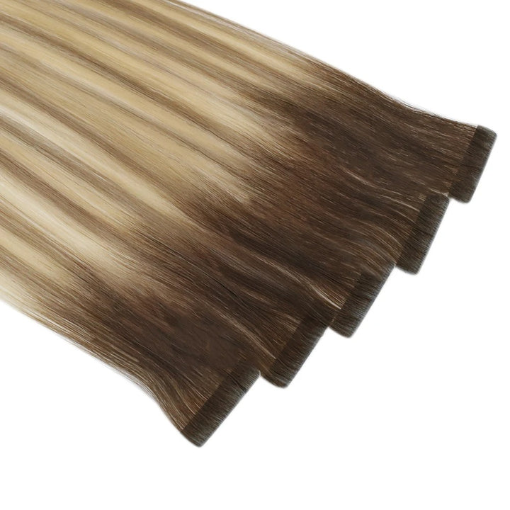 Two hair extensions with a gradient from blonde to brown on a white background